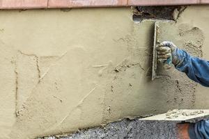 tegel arbeider toepassen cement met troffel Bij zwembad bouw plaats foto