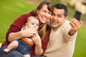 gelukkig gemengd ras ouders en baby jongen nemen zelf portretten foto