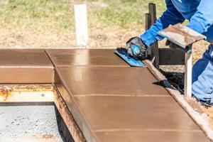 bouw arbeider gebruik makend van troffel Aan nat cement vormen omgaan in de omgeving van nieuw zwembad foto