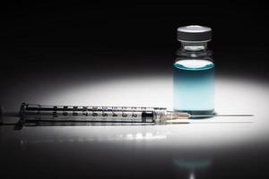 injectiespuit naald- en geneeskunde flacon met licht blauw chemisch plek lit Aan reflecterende achtergrond foto