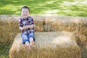 schattig jong gemengd ras jongen hebben pret Aan hooi baal foto