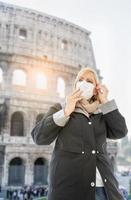 jong vrouw vervelend gezicht masker wandelingen in de buurt de de Romeins Coliseum in Rome, Italië foto