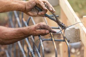 arbeider beveiligen staal wapening framing met draad tang snijder gereedschap Bij bouw plaats foto