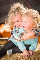 zoet weinig jongen Toneelstukken met zijn baby zus in een rustiek boerderij instelling Bij de pompoen lapje. foto