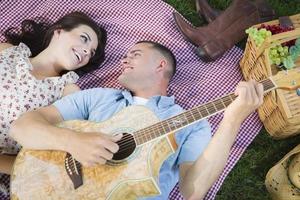 gemengd ras paar Bij de park spelen gitaar en het zingen foto