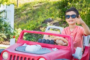 jong gemengd ras Chinese en Kaukasisch jongen vervelend zonnebril spelen in speelgoed- auto foto