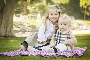 zoet weinig meisje met haar baby broer Bij de park foto