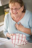 senior volwassen vrouw Bij wastafel met borst pijnen foto