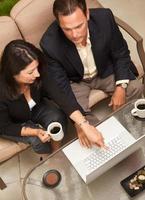 Mens en vrouw gebruik makend van laptop met koffie foto