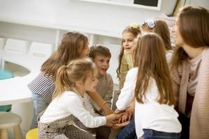 schattig peuter- kinderen zetten handen samen met hun kinderkamer leraar foto