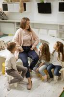kinderkamer leraar pratend verhaal naar groep van kinderen zittend Aan een stoelen Bij kleuterschool foto