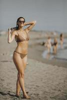 jong vrouw in bikini staand door de zee Aan een zomer dag foto