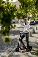 jonge Afro-Amerikaanse met behulp van elektrische scooter op een straat foto