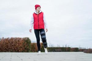 vrouw vervelend knie beugel of orthese na been chirurgie wandelen in de park foto