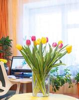 knus huis vakantie 8 maart, verjaardag, Valentijn dag met tulpen vaas met huis werkplaats Aan achtergrond. foto