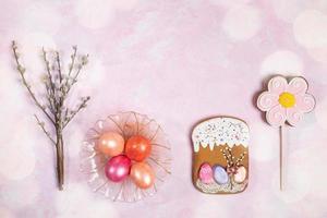 rij van Pasen decoraties kleur eieren in glas bord, Pasen peperkoeken, wilg twijgen en bokeh Aan roze achtergrond. foto