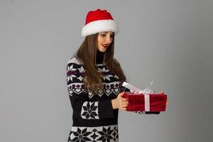vrouw in warm trui en de kerstman hoed met rood geschenk foto