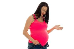 mooi zwanger brunette vrouw met groot buik poseren in roze overhemd geïsoleerd Aan wit achtergrond foto