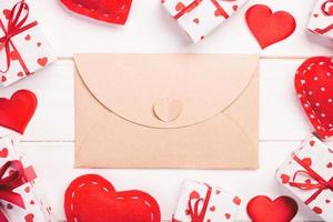 envelop mail met rood hart en geschenk doos over- houten tafel achtergrond. Valentijn dag kaart, liefde of bruiloft groet concept foto