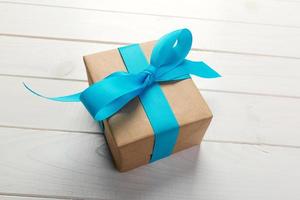 gerecycled papier geschenk doos met blauw lint Aan oud houten wit achtergrond.top visie foto