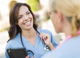 twee jong volwassen vrouw artsen of verpleegsters pratend buiten foto