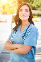 portret van jong volwassen vrouw dokter of verpleegster vervelend scrubs en stethoscoop buiten. foto