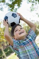 schattige jonge jongen speelt met voetbal buiten in het park. foto