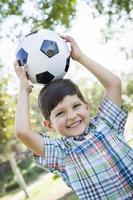 schattige jonge jongen spelen met voetbal in park foto