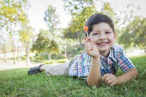 jong jongen genieten van zijn lolly buitenshuis houdende Aan gras foto