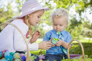 schattige jonge broer en zus genieten van hun paaseieren buiten foto