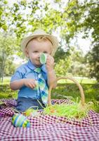 schattige kleine jongen genieten van zijn paaseieren buiten in park foto