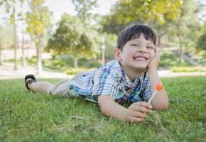 jong jongen genieten van zijn lolly buitenshuis houdende Aan gras foto