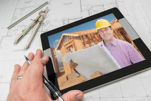architect hand- Aan tablet tonen aannemer over- huis plannen foto