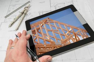 architect hand- Aan tablet tonen huis framing over- huis plannen foto