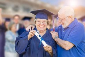 senior volwassen vrouw in pet en japon wezen gefeliciteerd door man Bij buitenshuis diploma uitreiking ceremonie. foto