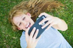 jong volwassen vrouw houdende in gras nemen een selfie met haar slim telefoon. foto