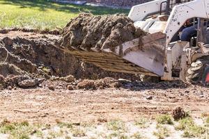 klein bulldozer graven in werf voor zwembad installatie foto