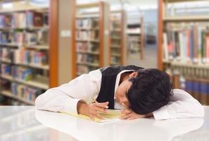 jong vrouw gemengd ras leerling benadrukt en gefrustreerd in bibliotheek met blanco stootkussen van papier. foto