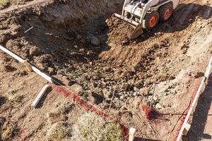 klein bulldozer graven in werf voor zwembad installatie foto