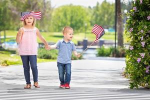 jong zus en broer golvend Amerikaans vlaggen Bij de park foto