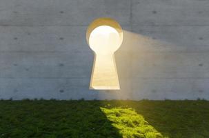 helder zon licht schijnend door sleutelgat in beton muur in gras en rotsen veld. foto