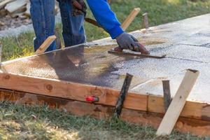 bouw arbeider gladmaken nat cement met troffel gereedschap foto