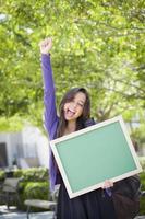 opgewonden gemengd ras vrouw leerling Holding blanco schoolbord foto