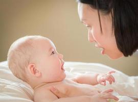 gemengd ras Chinese en Kaukasisch baby jongen houdende in bed met zijn moeder foto