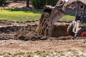 klein bulldozer graven in werf voor zwembad installatie foto