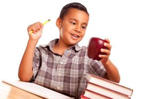 aanbiddelijk spaans jongen met boeken, appel, potlood en papier foto