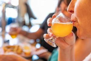 vrouw nippen glas van micro brouwen bier Bij bar met vrienden foto