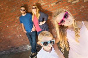 schattig jong Kaukasisch broer en zus vervelend zonnebril met ouders achter foto