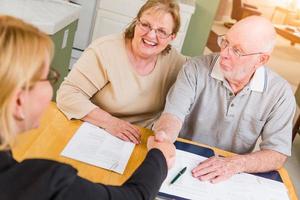 senior volwassen paar gaan over- documenten in hun huis met middel Bij ondertekening foto