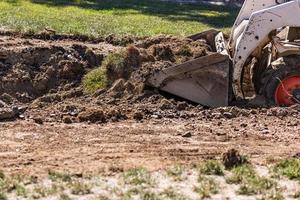 klein bulldozer graven in werf voor zwembad installatie foto